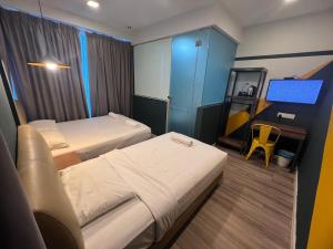 a hotel room with two beds and a desk at Smile Hotel Subang Airport in Shah Alam