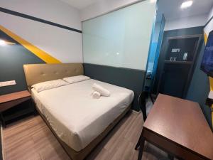 a small bedroom with a bed and a table at Smile Hotel Subang Airport in Shah Alam
