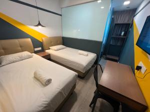 a room with two beds and a table and a desk at Smile Hotel Subang Airport in Shah Alam