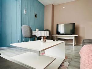 a living room with a white table and a tv at Midtown Apartment in Kŭrdzhali