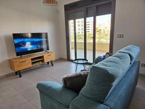 Il comprend un salon doté d'un canapé bleu et d'une télévision à écran plat. dans l'établissement Happy Place Apartament, à Arenales del Sol