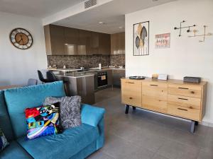 a living room with a blue couch and a kitchen at Happy Place Apartament in Arenales del Sol