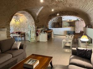 a living room with couches and a table and a kitchen at Can Clotas Hotel Masia in Cistella