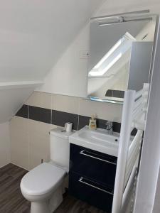 a white bathroom with a toilet and a sink at Maison Bord de Mer dans la Petite Irlande in Auderville