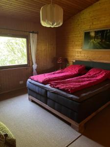a bedroom with a large bed with red sheets and a window at Alb Landhaus in Inneringen-Hettingen