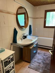 een badkamer met een wastafel, een spiegel en een bad bij Alb Landhaus in Inneringen-Hettingen