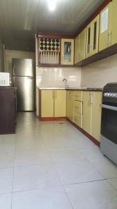 a kitchen with yellow cabinets and a stainless steel refrigerator at Avi Guest House in Addis Ababa