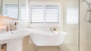 a white bathroom with a tub and a sink at Halcyon in Kiama