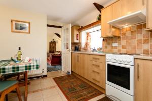 uma cozinha com um fogão branco forno superior ao lado de uma mesa em Swallows Cottage nr Warkworth em Acklington