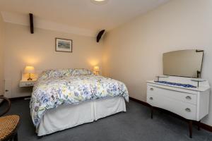 um quarto com uma cama e uma cómoda com um espelho em Swallows Cottage nr Warkworth em Acklington