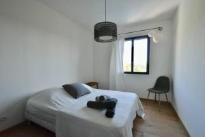 ein Schlafzimmer mit einem weißen Bett mit einem schwarzen Objekt darauf in der Unterkunft Villa moderne, calme avec piscine proche d'Aix-en-Provence in Châteauneuf-le-Rouge