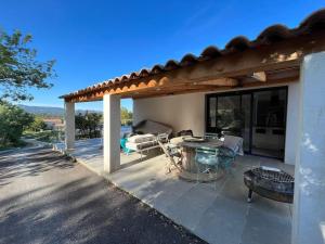 eine Terrasse mit einem Tisch und Stühlen unter einer Pergola in der Unterkunft Villa moderne, calme avec piscine proche d'Aix-en-Provence in Châteauneuf-le-Rouge