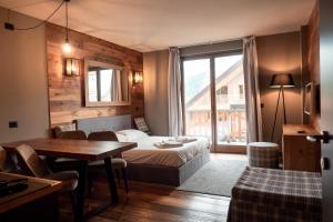 a hotel room with a bed and a table and a window at Chalet Everest - Luxury Apartments in Prato Nevoso