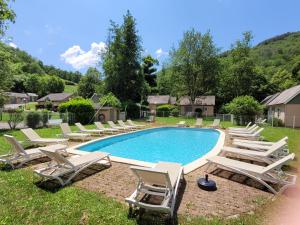a pool with chaise lounge chairs and a bunch at Village de 19 gites avec Piscine et restaurant, Grand Vabre Nature in Conques