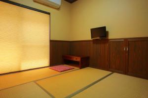 a room with a tv and a table and a window at Family Ryokan Kawakyu with Showa Retro in Ibusuki