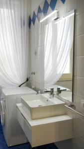 Baño blanco con lavabo y espejo en Donna Elena House, en Maiori