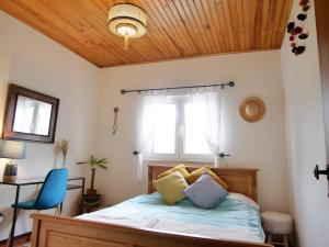 a bedroom with a bed with a window and a blue chair at Sonhos Cósmicos in Barril de Alva