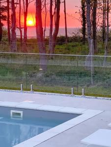 una piscina con puesta de sol en el fondo en CLIFF Trzęsacz - sea view apartments, en Trzęsacz