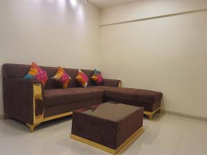 uma sala de estar com um sofá castanho com almofadas coloridas em OSI Apartments Santacruz em Mumbai