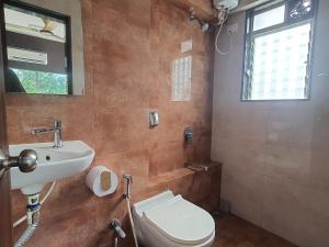 uma casa de banho com um lavatório, um WC e uma janela. em OSI Apartments Santacruz em Mumbai