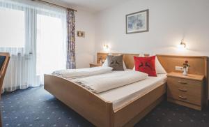 a bedroom with a large bed with red pillows at Garni Appartement Alpenresidence in Cadipietra