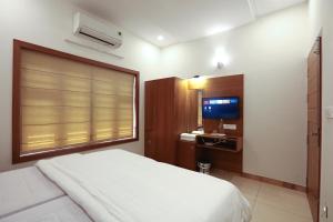 a bedroom with a white bed and a television at Choice Beach House in Kannur