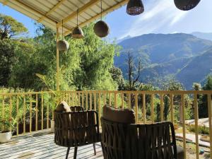 a balcony with two chairs and a view of a mountain at Eco Farmstay Cottages #1 in Dharamshala