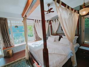 a bedroom with a canopy bed with a window at Eco Farmstay Cottages #1 in Dharamshala