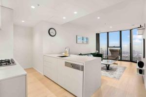cocina y sala de estar con reloj en la pared en Glamorous 2BR Southbank home LV50! stunning view#MSQ5003, en Melbourne