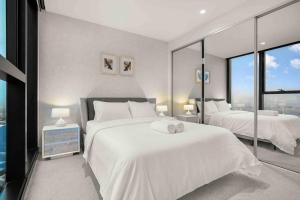 1 dormitorio con 2 camas, sábanas blancas y ventanas en Glamorous 2BR Southbank home LV50! stunning view#MSQ5003, en Melbourne
