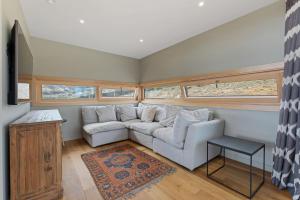 a living room with a couch and two windows at Vino and Views - Bannockburn Holiday Home in Cromwell