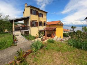a yellow house on a hill with the ocean in the background at Apartment Adria Lovran in Lovran