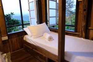um quarto com uma cama com janelas e um chapéu em Camp-Ula em Sampalok