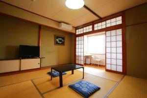 a living room with a table and a television at Family Ryokan Kawakyu with Showa Retro in Ibusuki
