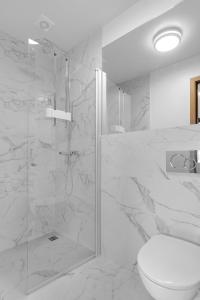 een witte badkamer met een douche en een toilet bij Klettar - The Old Hatchery Iceland in Fludir