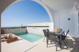 un patio con una mesa y una piscina en Muses of art Villas en Afántou