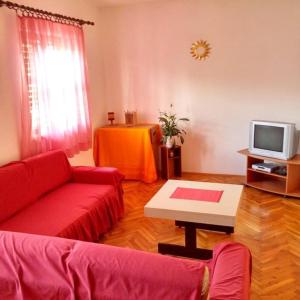 uma sala de estar com um sofá vermelho e uma televisão em Apartman PEGRE - NO A/C em Supetar