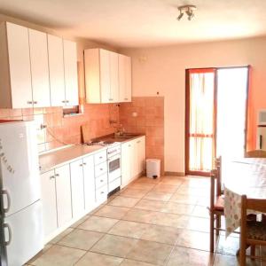 uma cozinha com armários brancos e piso em azulejo em Apartman PEGRE - NO A/C em Supetar