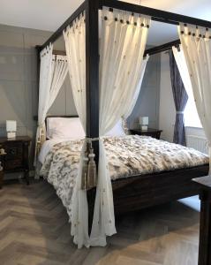 a bedroom with a canopy bed with white curtains at Cleomack House - Perfect for two in Hilltown