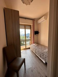 1 dormitorio con 1 cama, 1 silla y 1 ventana en hotel La pineta en Carrara