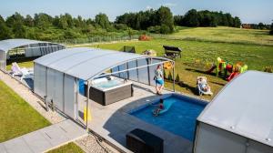 a woman is standing next to a swimming pool in a tent at Apartamenty Mazurski Rejs in Węgorzewo