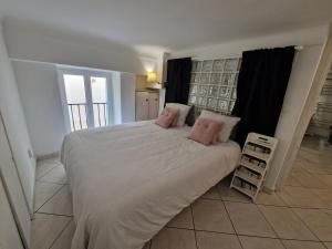 a bedroom with a large white bed with pink pillows at Le Cosy - Hyper Center 2 room apartment in Nice