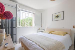 ein weißes Schlafzimmer mit einem Bett und einem Fenster in der Unterkunft U Momentu - appt climatisé avec terrasse in LʼÎle-Rousse