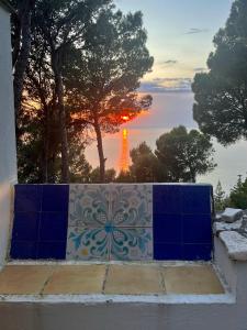 - un coucher de soleil sur l'océan avec un mur de carrelage bleu et blanc dans l'établissement Casa Mia Casa di Charme, à Santa Maria di Castellabate