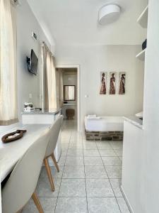 ein weißes Badezimmer mit einer Badewanne sowie einem Tisch und Stühlen in der Unterkunft Manto Apartments in Tinos