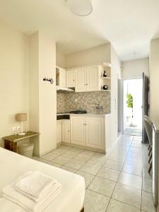 a kitchen with white cabinets and a tile floor at Manto Apartments in Tinos