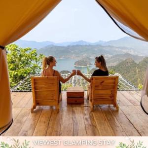 two women sitting on a deck holding hands at BAKHAN VIEWEST GLAMPING in Mai Chau