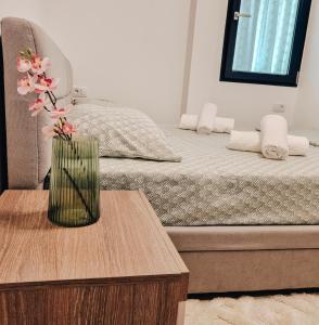 un jarrón de flores sentado en una mesa junto a una cama en Bijou Aparthotel en Galaţi