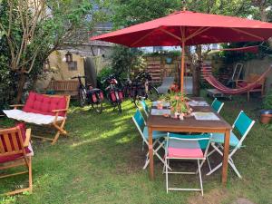 uma mesa e cadeiras debaixo de um guarda-sol vermelho num quintal em Auberge du Finistère - Chambres Cosy à louer - Bienvenus chez Anne votre hote et Chris le gardien- proche centre ville et odet à pieds em Quimper