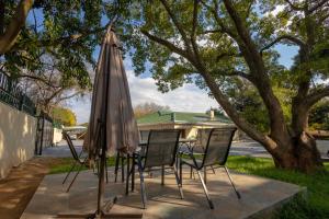 una mesa y sillas con una sombrilla en el patio en Greenshade Lodge, en Johannesburgo